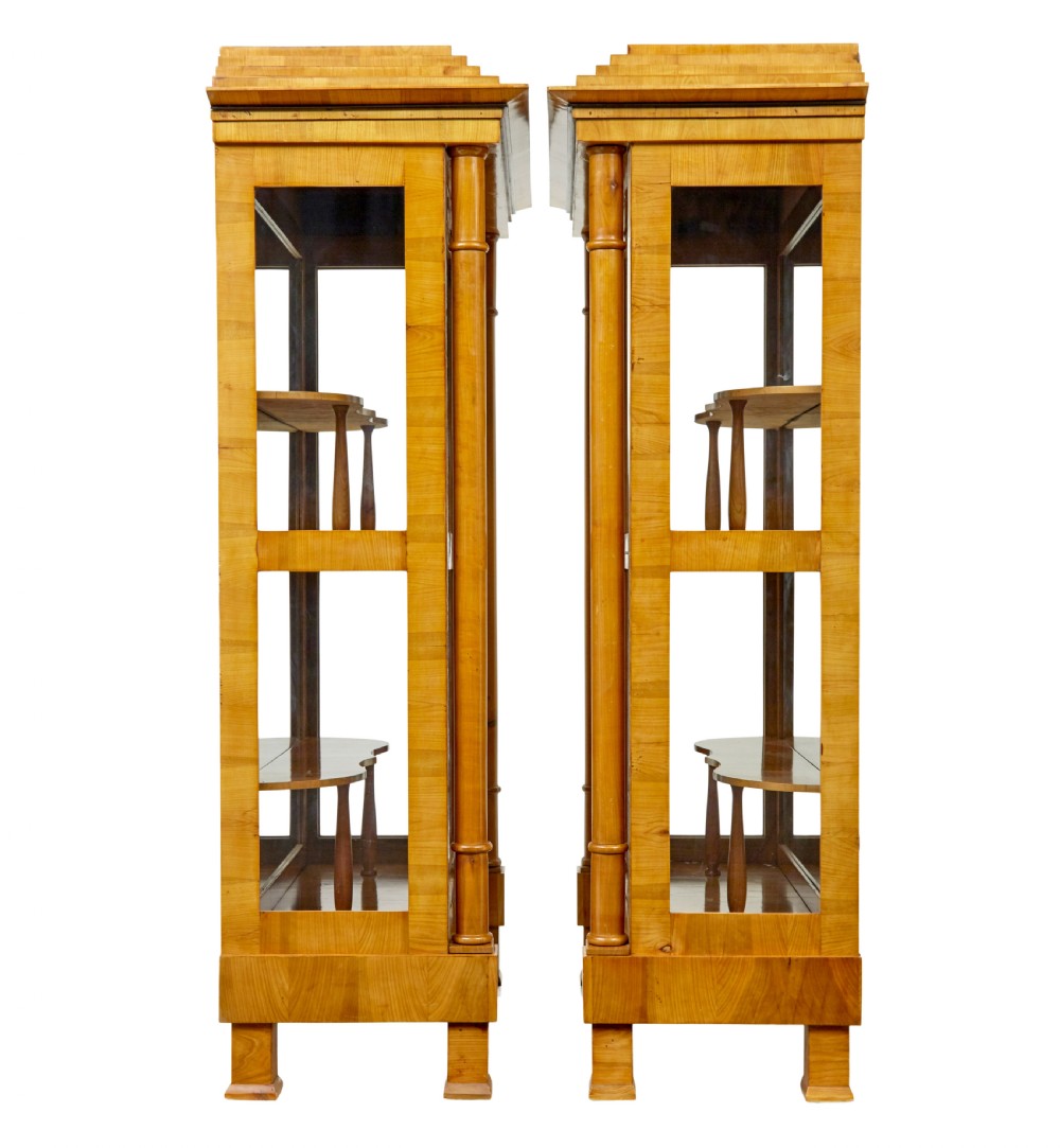 A matching pair of Biedermeier elm display cabinets with glazed doors, side columns, and stepped cornices. View V