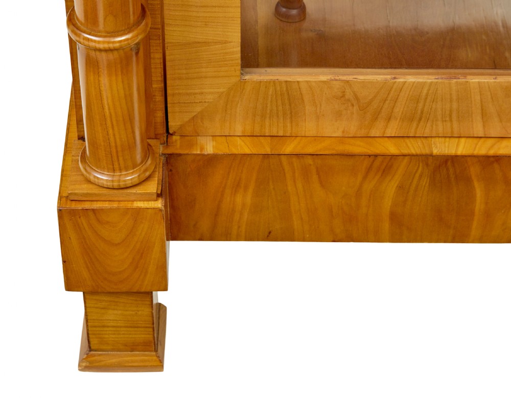 A matching pair of Biedermeier elm display cabinets with glazed doors, side columns, and stepped cornices. View X