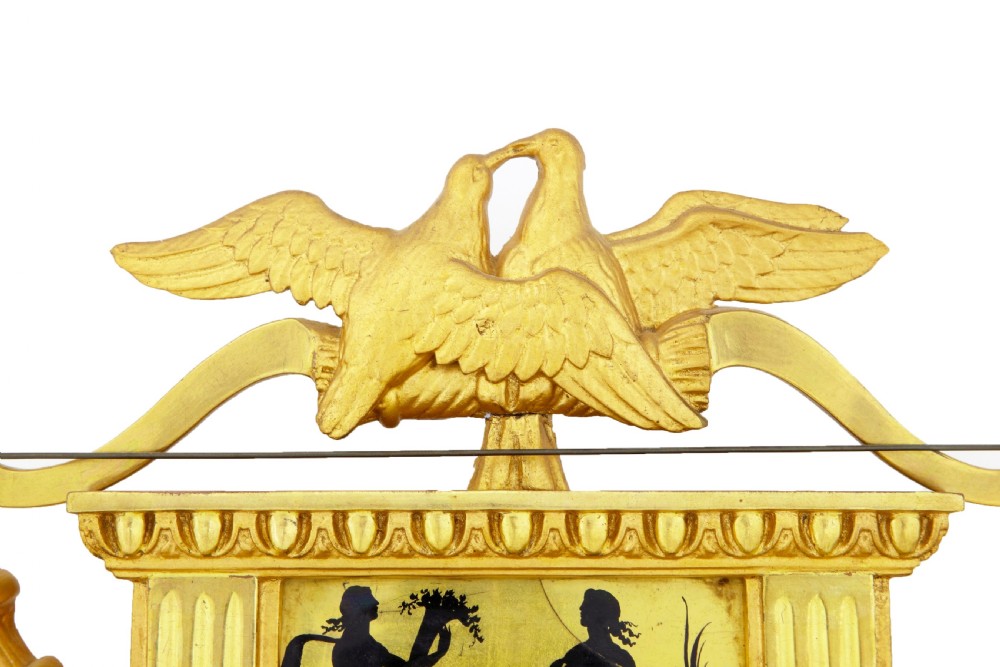 Nineteenth-century Swedish giltwood wall clock adorned with classical silhouettes on eglomise glass panels, carved urns, swags, and twin crested doves. View IV