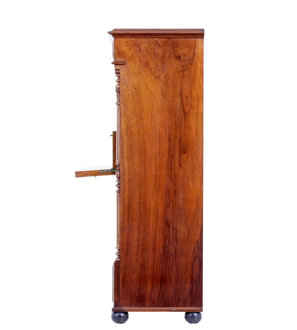 A tall 19th-century burr walnut secretaire chest of drawers featuring bookmatched veneer drawer fronts, fluted side columns, and ornate metal escutcheons. View VI