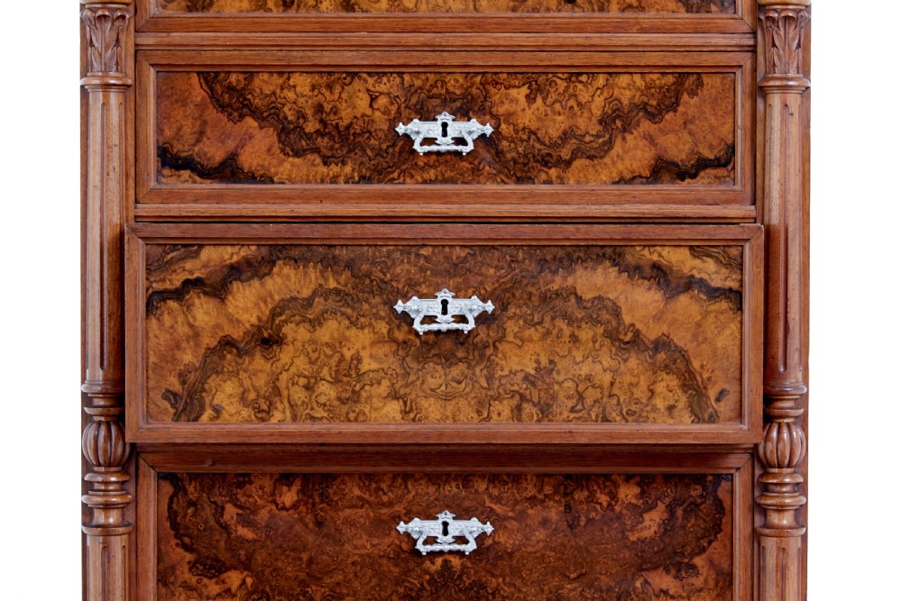 A tall 19th-century burr walnut secretaire chest of drawers featuring bookmatched veneer drawer fronts, fluted side columns, and ornate metal escutcheons. View IX