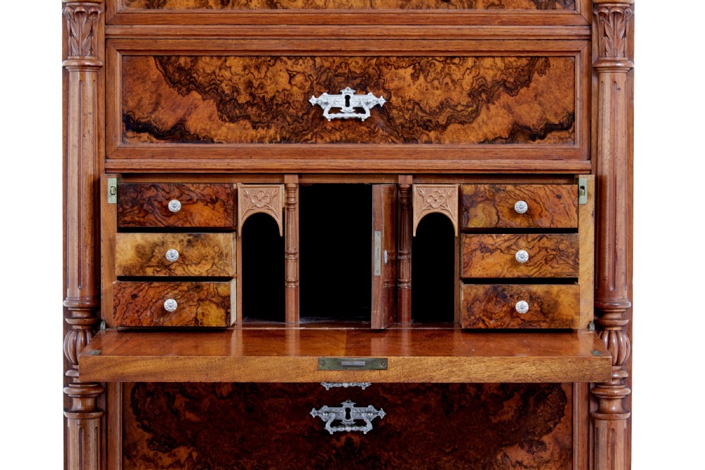 A tall 19th-century burr walnut secretaire chest of drawers featuring bookmatched veneer drawer fronts, fluted side columns, and ornate metal escutcheons. View XII