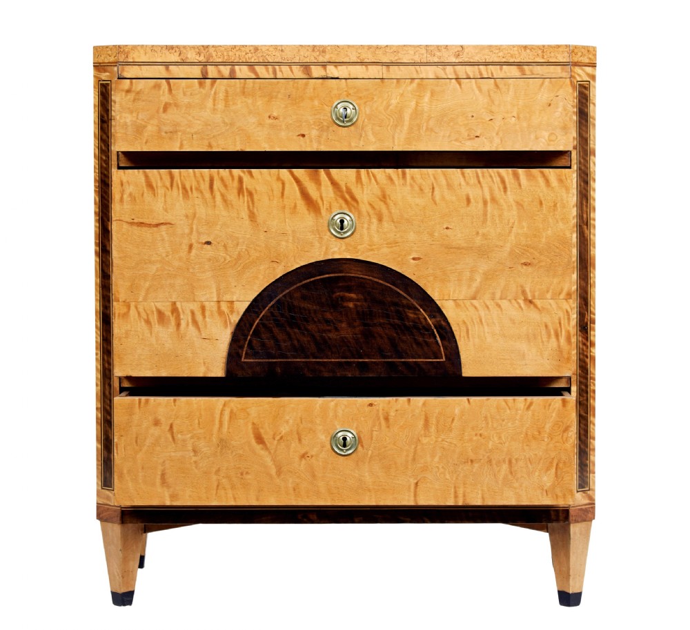A 19th-century Swedish birch chest of drawers featuring three drawers, flame grain veneers, dark timber inlay, and brass keyhole escutcheons on tapered legs. View III