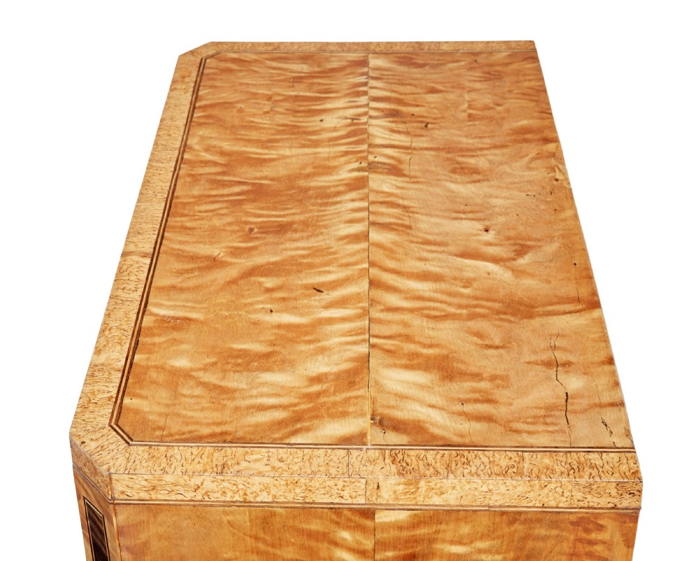 A 19th-century Swedish birch chest of drawers featuring three drawers, flame grain veneers, dark timber inlay, and brass keyhole escutcheons on tapered legs. View IX