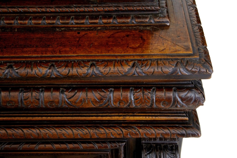 A two-section mid-19th century dark walnut cabinet featuring detailed relief carvings on the panelled doors, fluted columns, and flattened bun feet. View IX