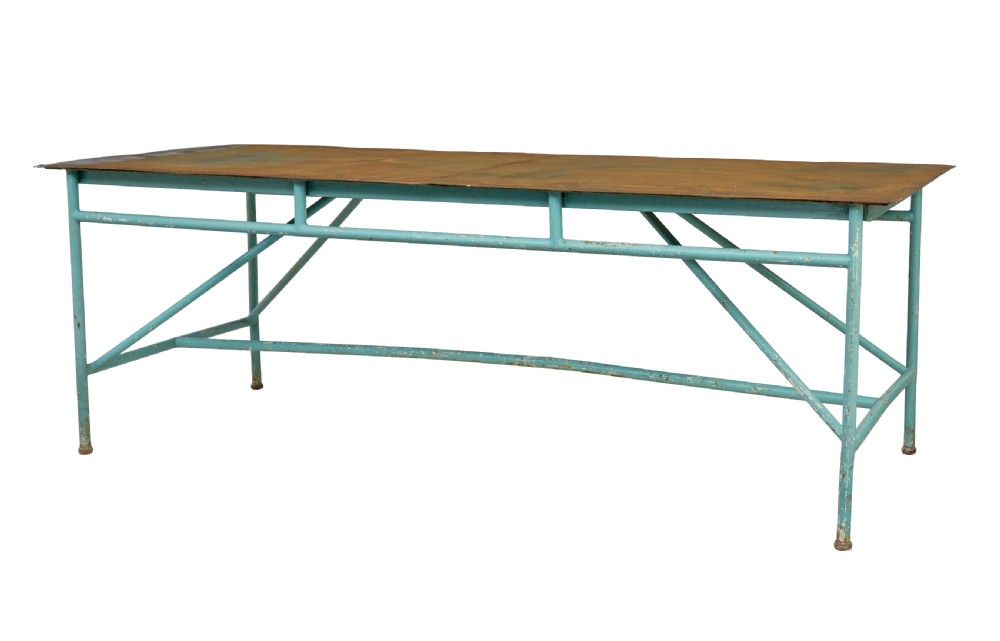 A large 1920s industrial table featuring a turquoise painted tubular steel frame with diagonal bracing and a flat rusty steel top.