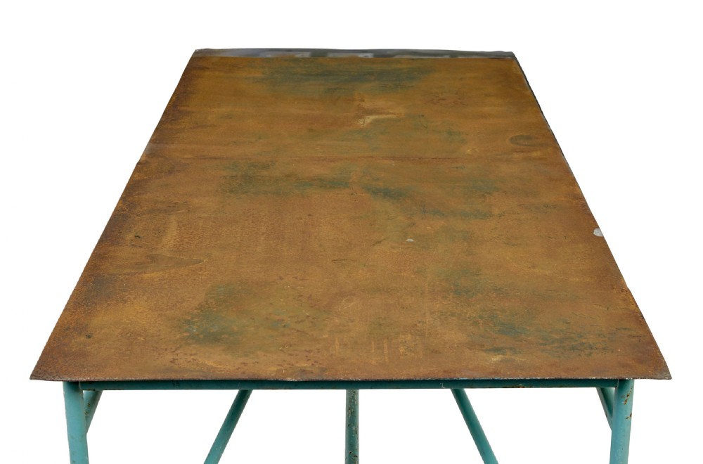 A large 1920s industrial table featuring a turquoise painted tubular steel frame with diagonal bracing and a flat rusty steel top. View VI