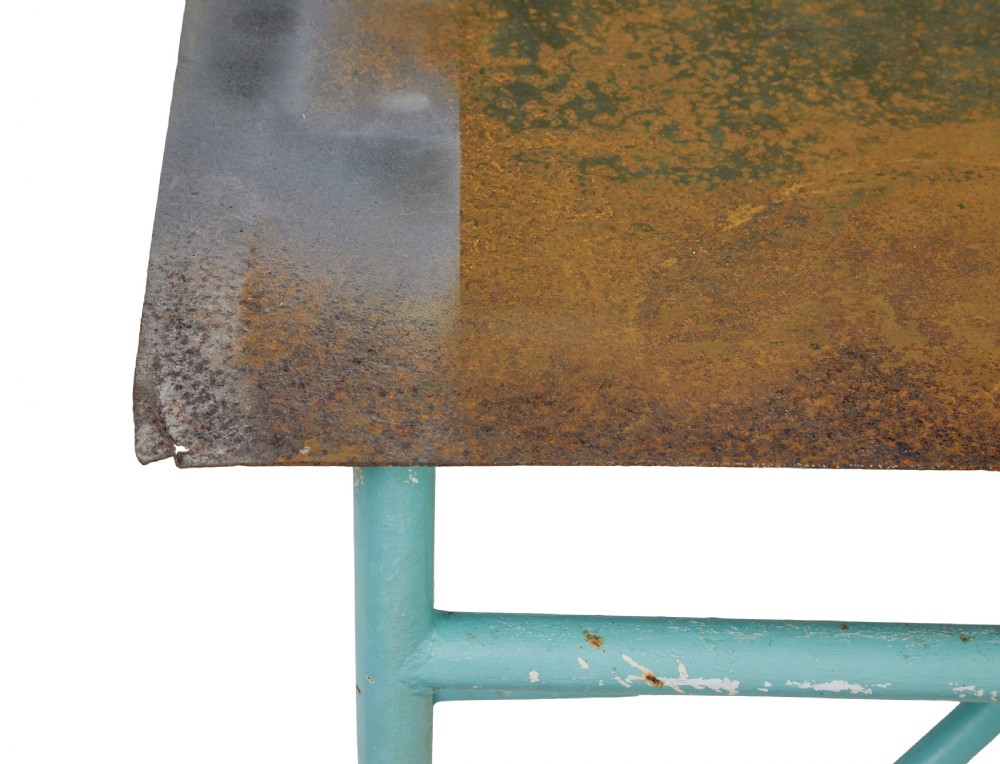 A large 1920s industrial table featuring a turquoise painted tubular steel frame with diagonal bracing and a flat rusty steel top. View VIII