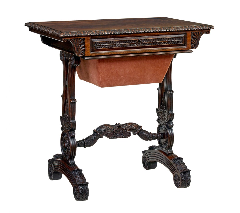 A 19th-century dark carved padouk wood side table featuring an integrated fabric work well and carved trestle legs.