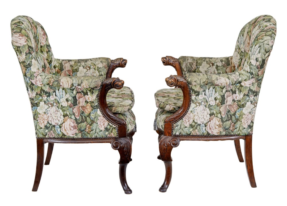 A pair of 19th-century French carved oak armchairs upholstered in a green floral tapestry fabric with carved lion-head armrests. View V