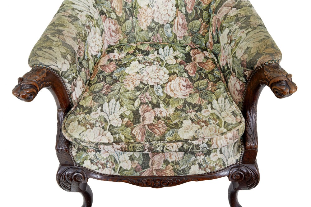A pair of 19th-century French carved oak armchairs upholstered in a green floral tapestry fabric with carved lion-head armrests. View VI