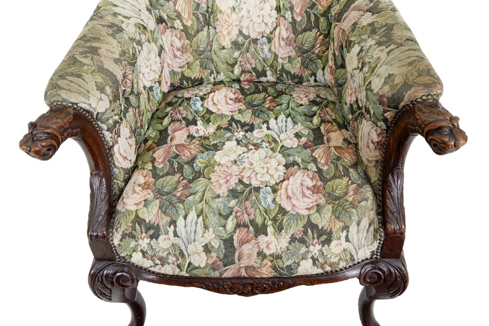 A pair of 19th-century French carved oak armchairs upholstered in a green floral tapestry fabric with carved lion-head armrests. View VII