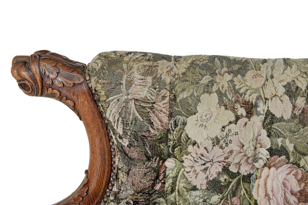 A pair of 19th-century French carved oak armchairs upholstered in a green floral tapestry fabric with carved lion-head armrests. View X