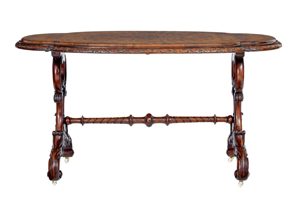 An oval 19th-century Victorian side table crafted from figured burr walnut with carved scroll legs, turned central stretcher, and ceramic castors. View II