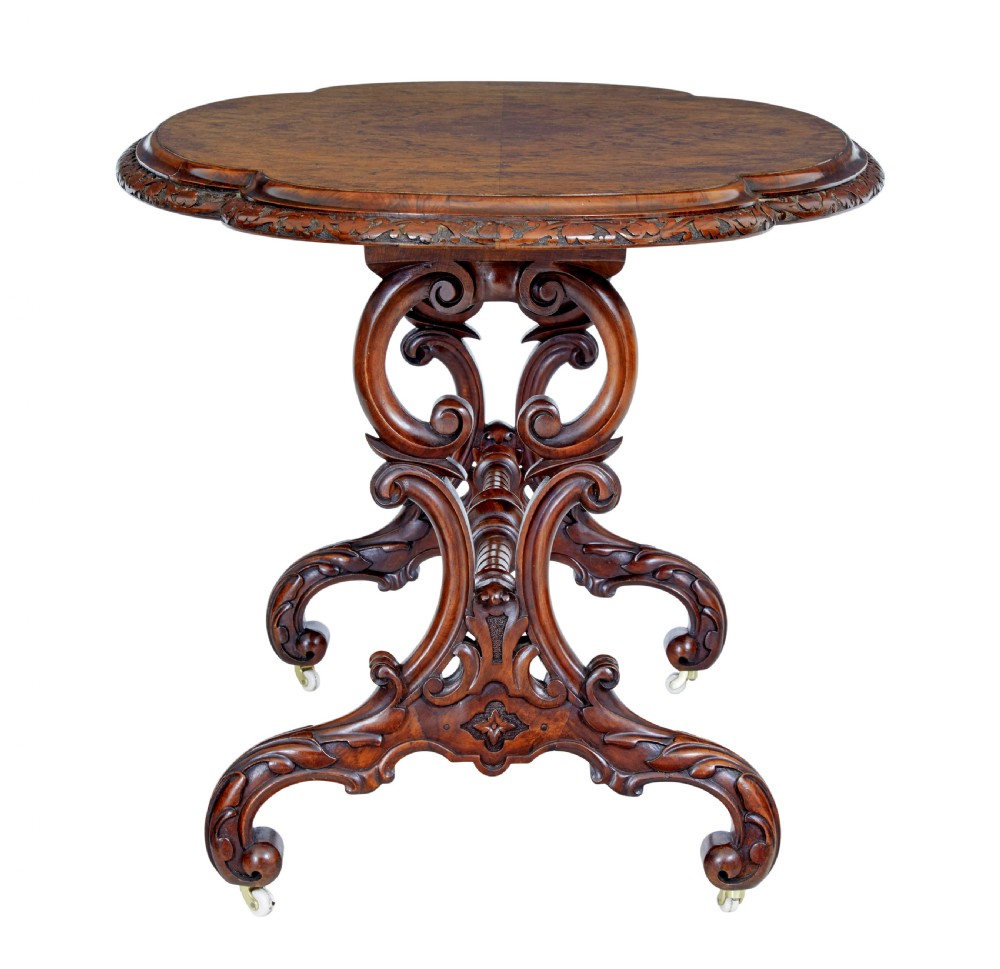 An oval 19th-century Victorian side table crafted from figured burr walnut with carved scroll legs, turned central stretcher, and ceramic castors. View III