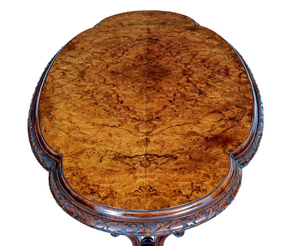 An oval 19th-century Victorian side table crafted from figured burr walnut with carved scroll legs, turned central stretcher, and ceramic castors. View IV
