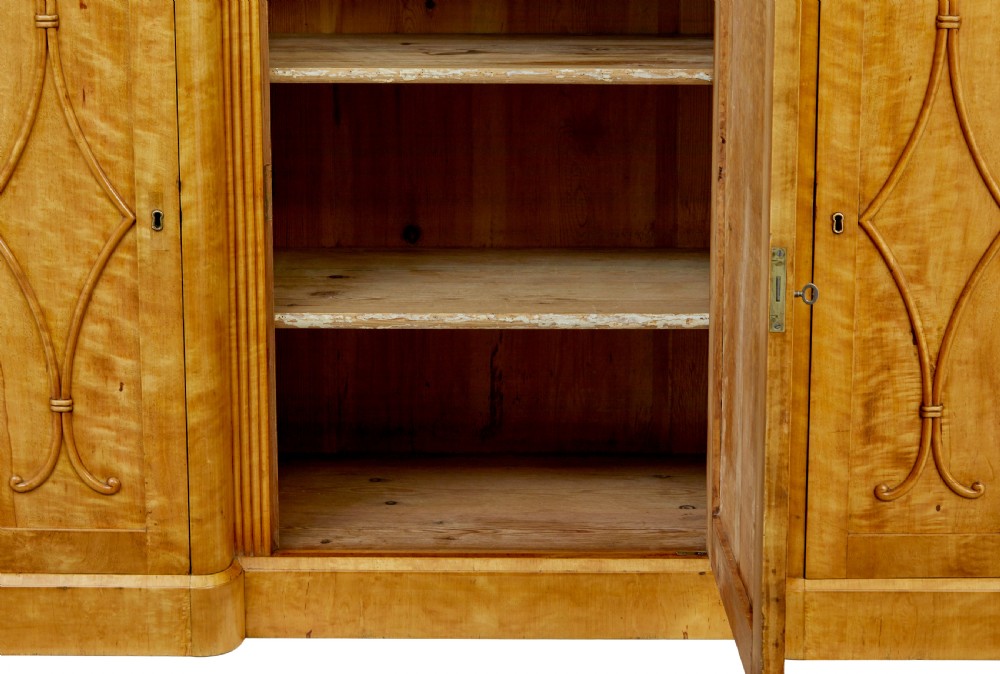 A mid-19th-century Swedish satin birch buffet sideboard featuring a lower three-door cabinet with carved petal applied mouldings and an upper tiered superstructure with Gothic arch cabinet doors. View VIII