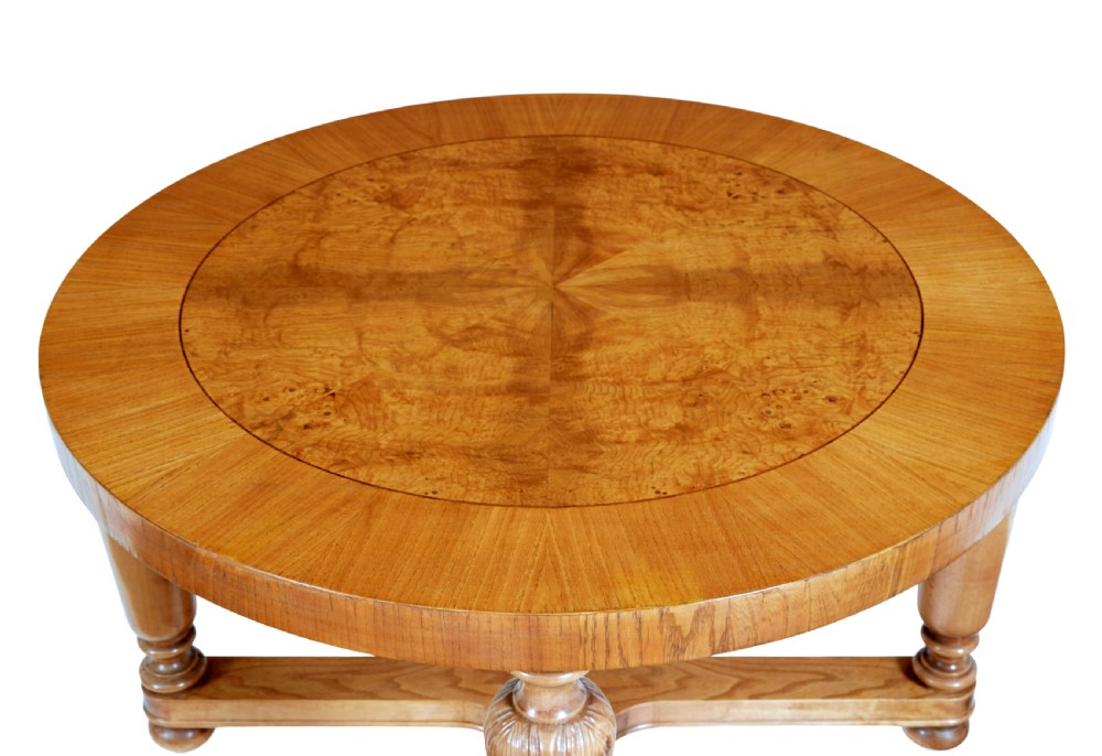 A low circular Art Deco coffee table crafted from light golden birch with an inlaid central panel and carved legs connected by an X-frame stretcher. View III