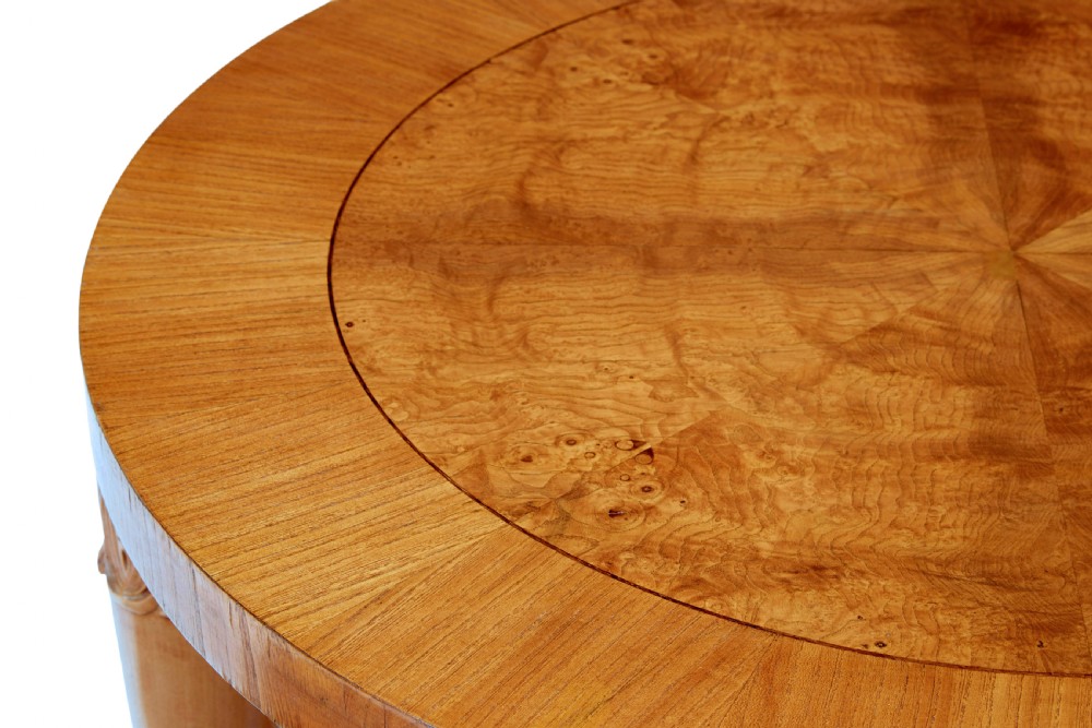 A low circular Art Deco coffee table crafted from light golden birch with an inlaid central panel and carved legs connected by an X-frame stretcher. View IV