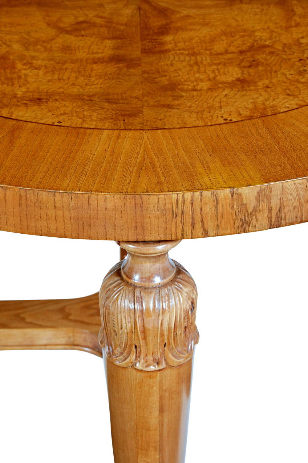 A low circular Art Deco coffee table crafted from light golden birch with an inlaid central panel and carved legs connected by an X-frame stretcher. View V