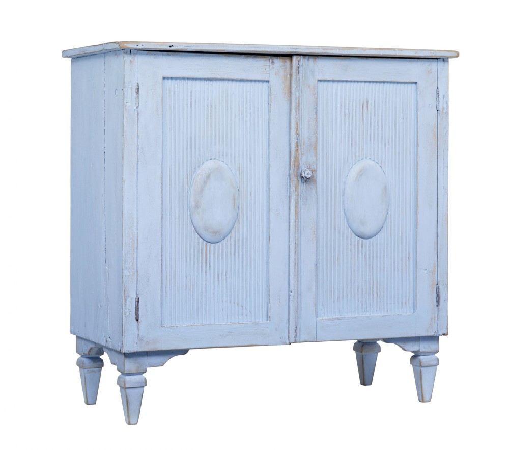 A 19th-century light blue painted pine two-door cupboard featuring reeded door panels with raised oval details and short turned feet.
