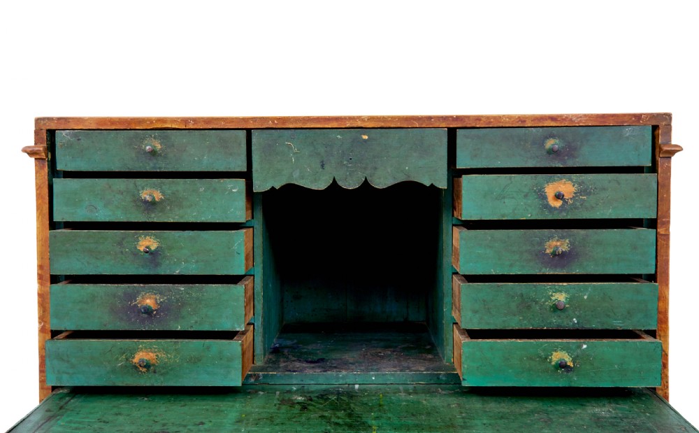 A 19th-century Swedish painted pine escritoire featuring a fall-front top section above three long drawers, finished in a faux-wood grain paint with brass drop handles and a scalloped plinth base. View X