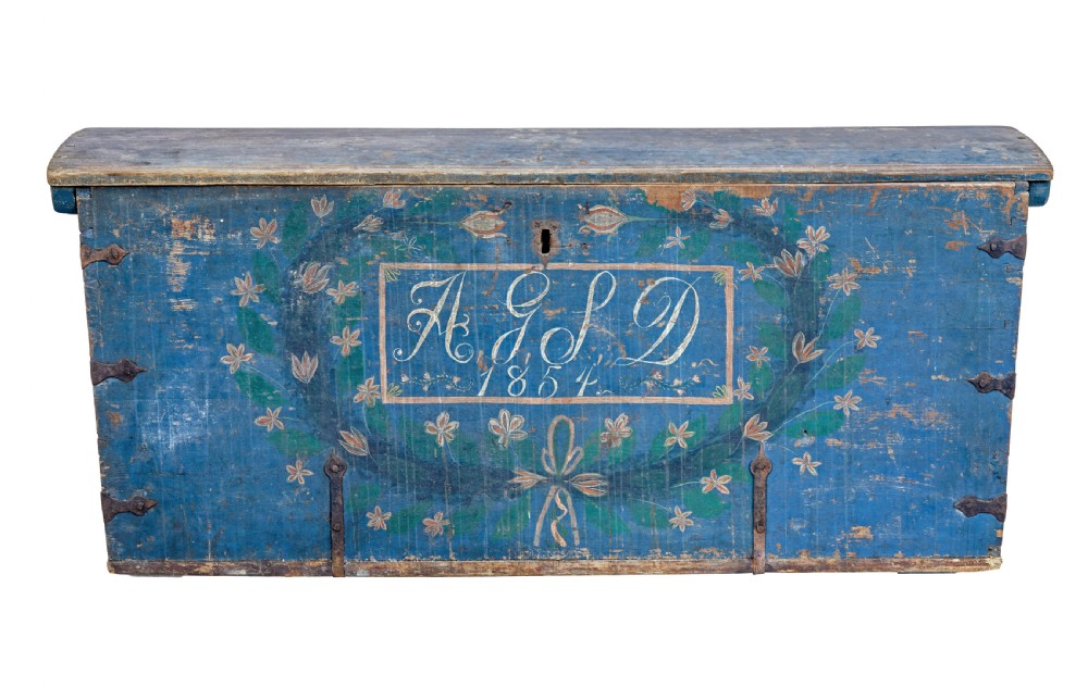 A nineteenth-century Swedish pine coffer painted in blue featuring hand-lettered initials AGSD dated 1854, floral wreath decoration, and wrought iron fittings.