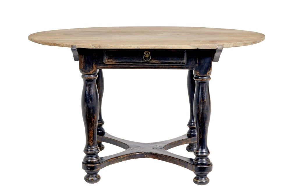A rustic 19th-century circular occasional table featuring a natural wood top, a dark painted base with a single drawer, turned legs, and an X-shaped cross-stretcher.