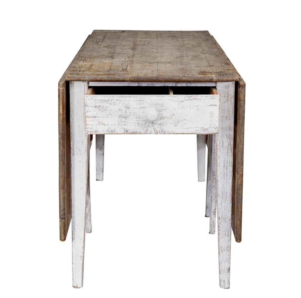 A 19th-century pine drop-leaf kitchen table featuring a natural wood top, hinged side flaps, end drawer, and a white-painted base with tapered square legs. View IV