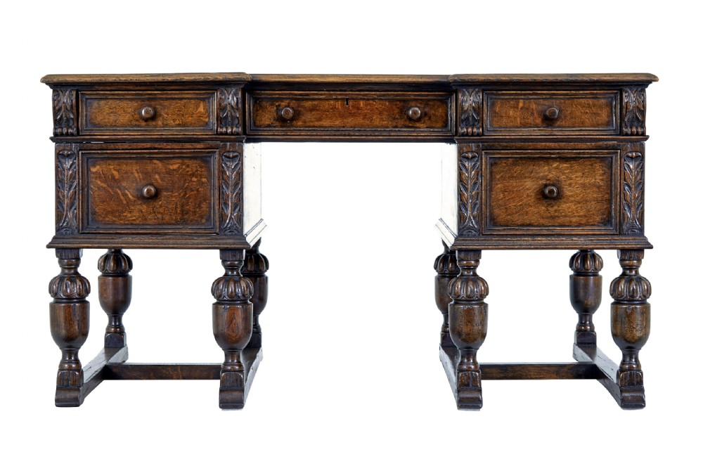 A late nineteenth-century Victorian dark carved oak pedestal desk featuring a leather writing surface, multiple drawers, and turned legs on stretcher bases. View II