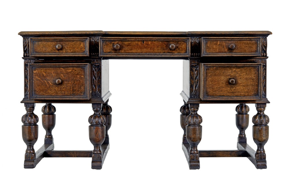 A late nineteenth-century Victorian dark carved oak pedestal desk featuring a leather writing surface, multiple drawers, and turned legs on stretcher bases. View III