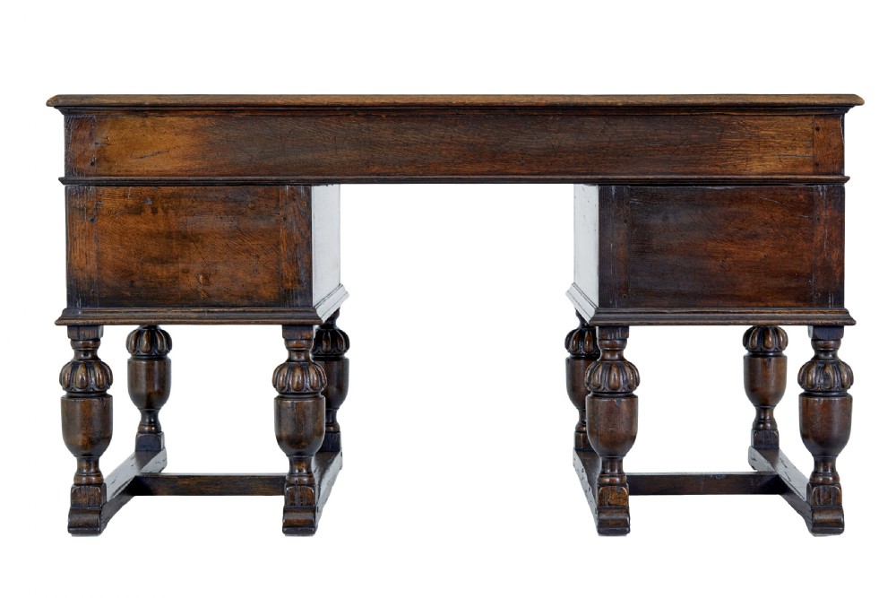 A late nineteenth-century Victorian dark carved oak pedestal desk featuring a leather writing surface, multiple drawers, and turned legs on stretcher bases. View VI