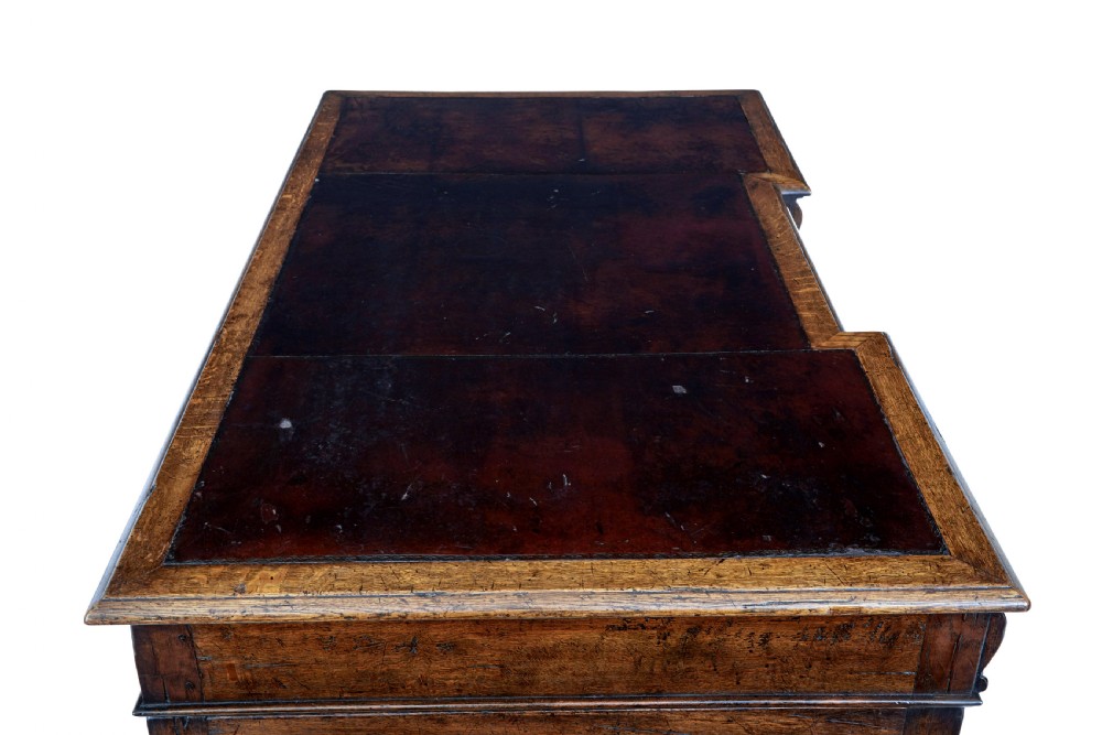 A late nineteenth-century Victorian dark carved oak pedestal desk featuring a leather writing surface, multiple drawers, and turned legs on stretcher bases. View X