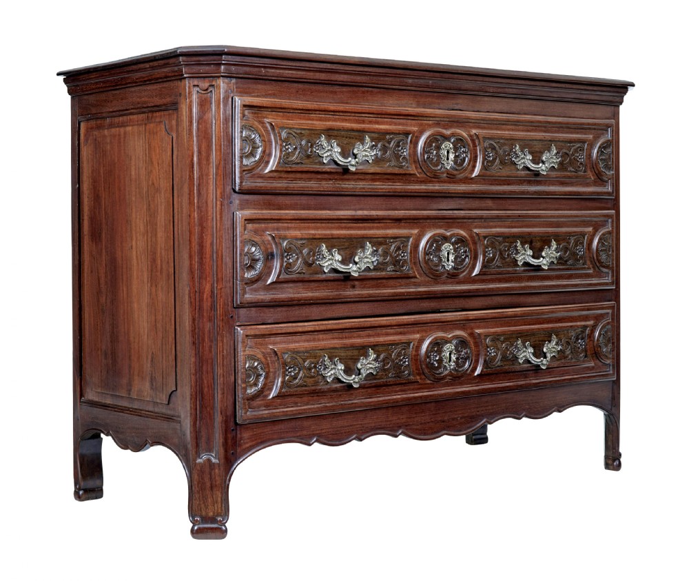 A 19th-century French Provincial walnut commode featuring three long carved drawers with brass handles and a scalloped lower apron.