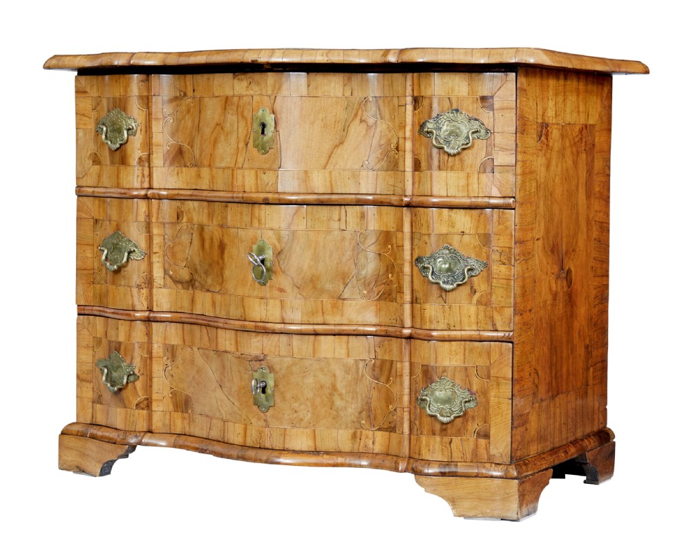 An 18th-century burr walnut serpentine-front chest of drawers featuring three long drawers with ornate brass handles and bracket feet.