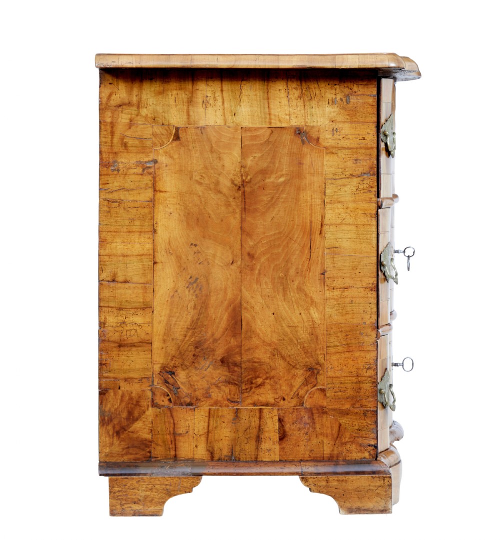 An 18th-century burr walnut serpentine-front chest of drawers featuring three long drawers with ornate brass handles and bracket feet. View VII