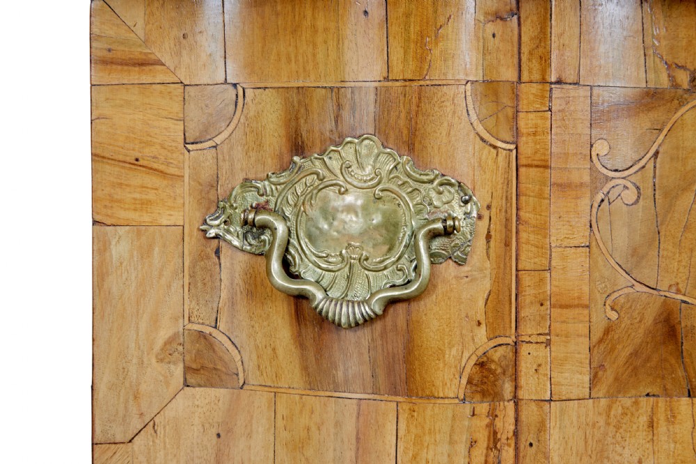 An 18th-century burr walnut serpentine-front chest of drawers featuring three long drawers with ornate brass handles and bracket feet. View VIII