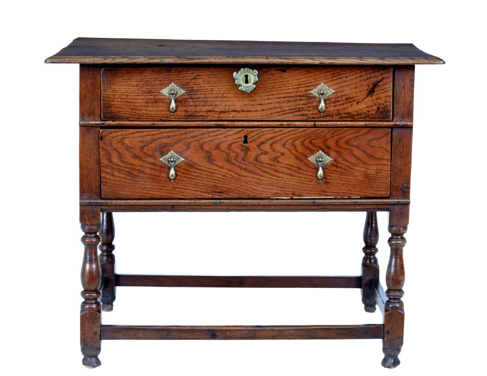 An early 18th-century Georgian oak side table featuring two drawers with brass drop handles, keyhole escutcheons, turned legs, and a box stretcher. View III
