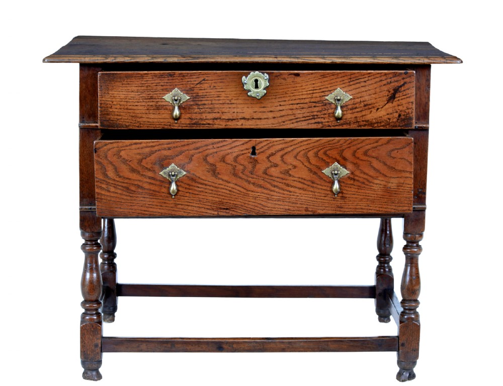 An early 18th-century Georgian oak side table featuring two drawers with brass drop handles, keyhole escutcheons, turned legs, and a box stretcher. View IV