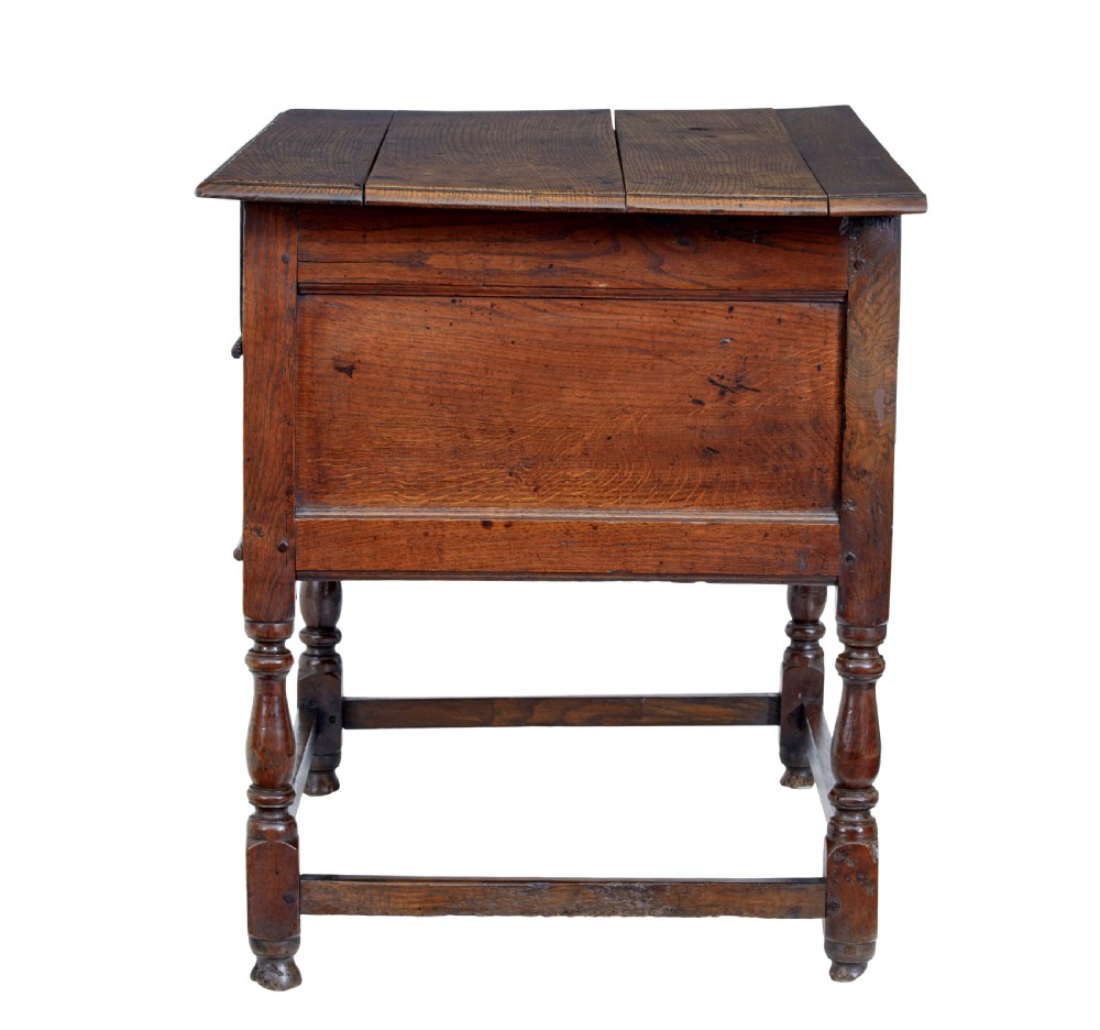 An early 18th-century Georgian oak side table featuring two drawers with brass drop handles, keyhole escutcheons, turned legs, and a box stretcher. View V