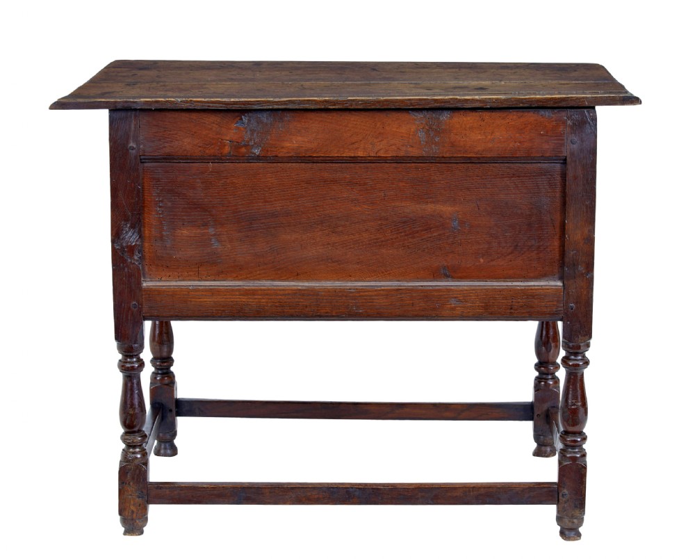 An early 18th-century Georgian oak side table featuring two drawers with brass drop handles, keyhole escutcheons, turned legs, and a box stretcher. View VI