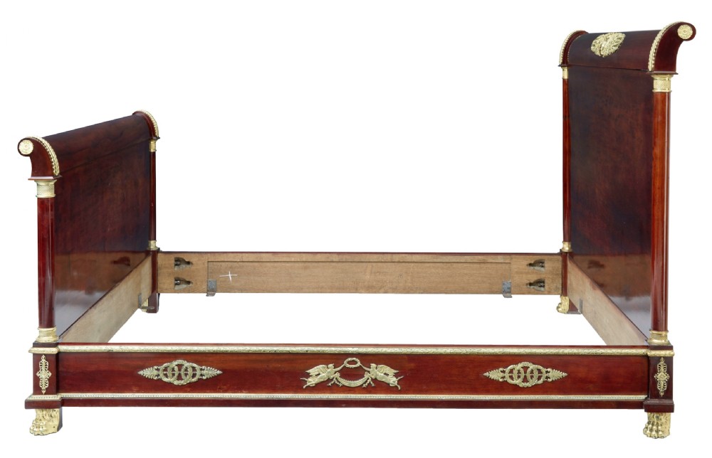 A five-piece nineteenth-century French Empire Revival mahogany bedroom suite featuring gilt bronze mounts, including a sleigh bed, a three-door mirrored wardrobe, a dressing table with mirror, and two matching bedside cabinets. View V