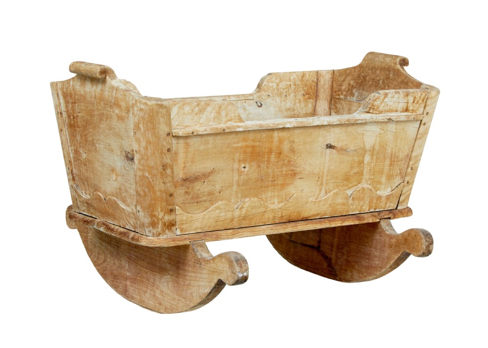 A mid-19th-century Swedish pine rocking cradle with hand-carved handles, scalloped edge detailing, and integrated wooden rockers. View II
