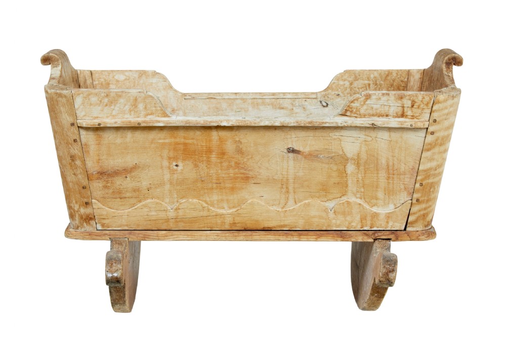 A mid-19th-century Swedish pine rocking cradle with hand-carved handles, scalloped edge detailing, and integrated wooden rockers. View IV