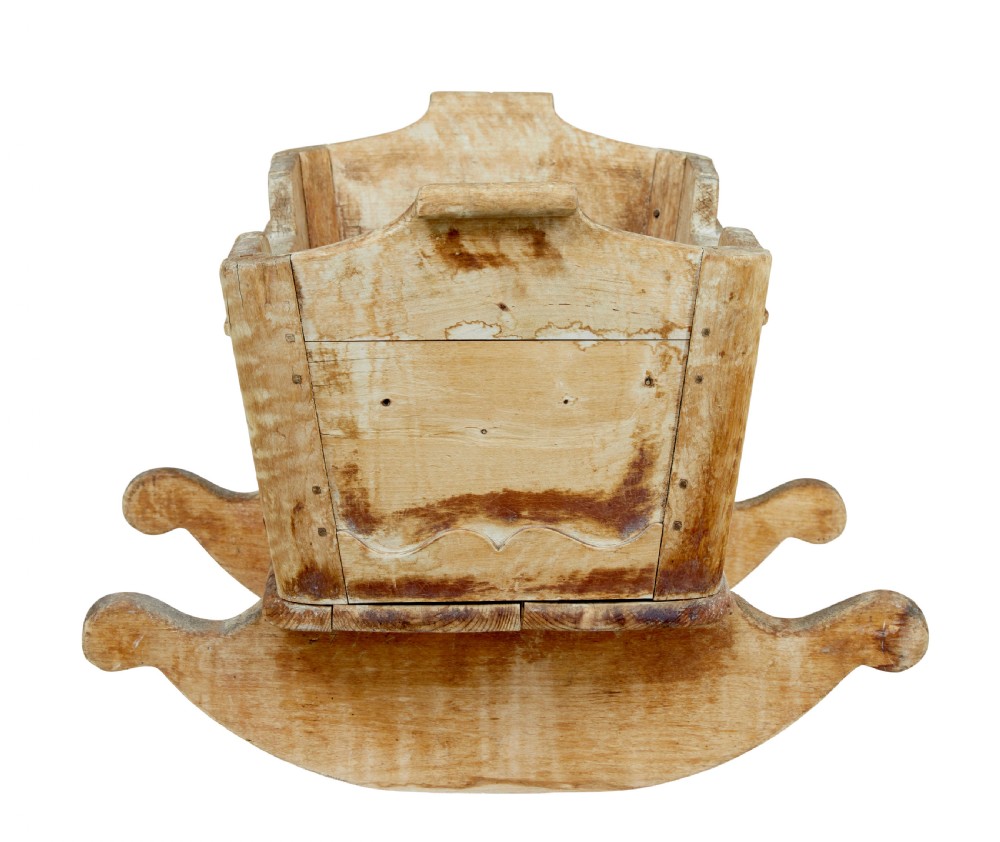 A mid-19th-century Swedish pine rocking cradle with hand-carved handles, scalloped edge detailing, and integrated wooden rockers. View V