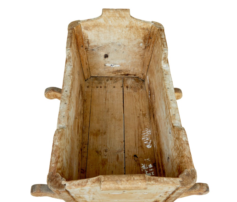A mid-19th-century Swedish pine rocking cradle with hand-carved handles, scalloped edge detailing, and integrated wooden rockers. View VII