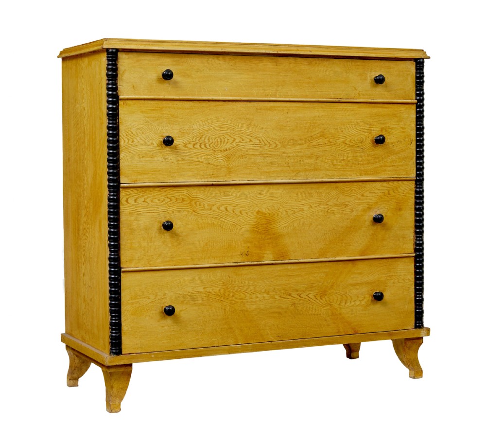 A mid-19th century Swedish northern pine chest of drawers featuring a yellow painted finish, four full-width drawers with black knobs, and black bobbin-turned corner columns.