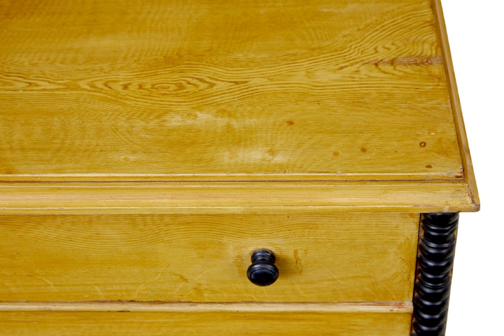 A mid-19th century Swedish northern pine chest of drawers featuring a yellow painted finish, four full-width drawers with black knobs, and black bobbin-turned corner columns. View V