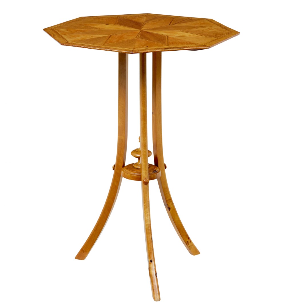 An early 20th-century octagonal occasional table made of light birch wood featuring a geometric starburst inlaid top and splayed legs.