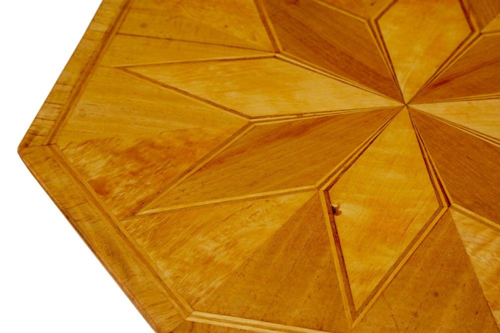 An early 20th-century octagonal occasional table made of light birch wood featuring a geometric starburst inlaid top and splayed legs. View VI